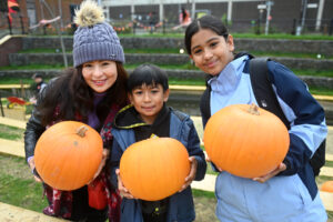 A mother and two children holding pumpkins at the free pumpkin patch in Luton, Hat Gardens last year