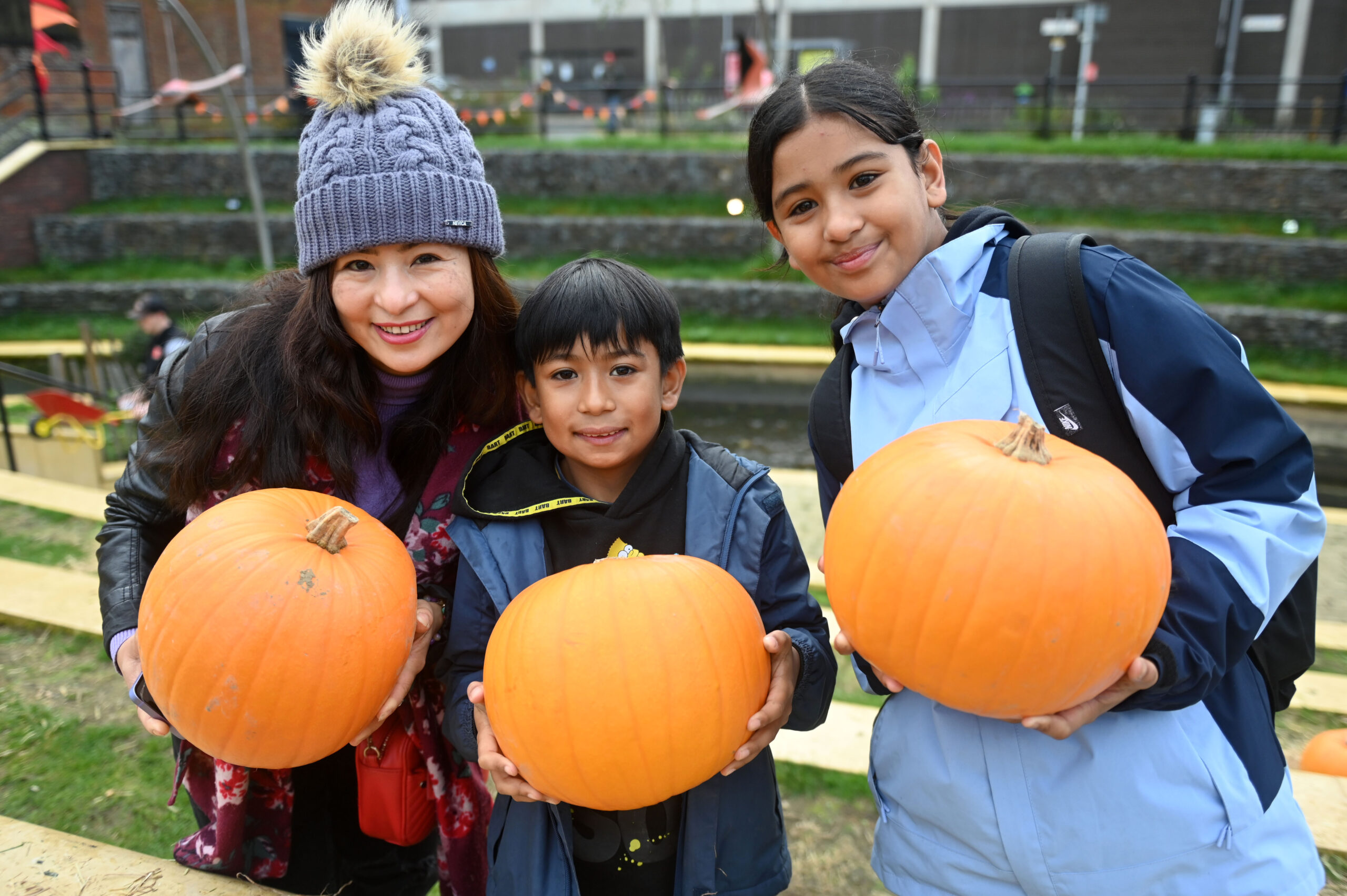 A mother and two children holding pumpkins at the free pumpkin patch in Luton, Hat Gardens last year